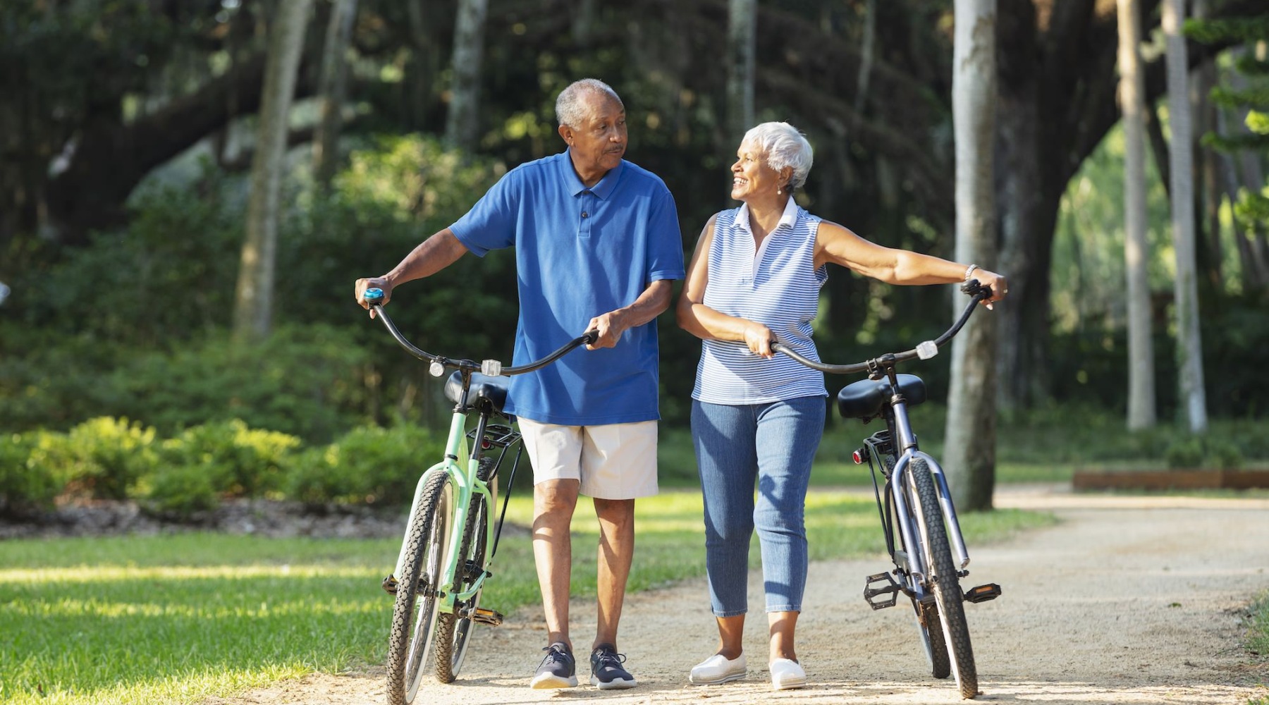 a man and woman holding hands while walking with a bicycle