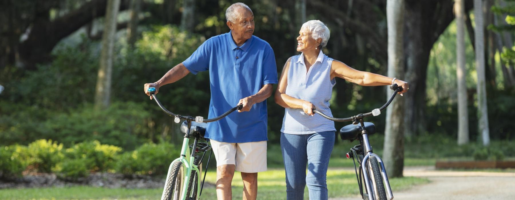 a man and woman holding hands while walking with a bicycle